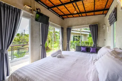 a bedroom with a large white bed with large windows at Loftpical Resort in Phuket Town