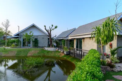 a house with a pond in front of it at Loftpical Resort in Phuket Town