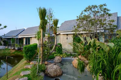 a house with a koi pond in front of it at Loftpical Resort in Phuket Town