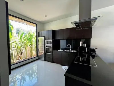 a kitchen with black cabinets and a large window at 3bdr Pool villa Naiharn KOK by Capital Pro in Rawai Beach