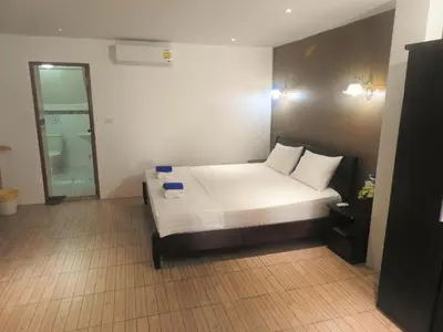 a bedroom with a bed with white sheets and pillows at Allstar Guesthouse in Karon Beach