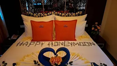 a bed with two red pillows and a blue heart shapedvisor at BAB ALHARA HOTEL in Patong Beach