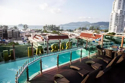 a view of a swimming pool with chairs and buildings at BAB ALHARA HOTEL in Patong Beach