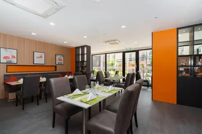 a dining room with tables and chairs and windows at KK Karon Kata Boutique Hotel in Kata Beach