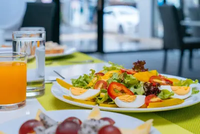 a plate of food with eggs and salad on a table at KK Karon Kata Boutique Hotel in Kata Beach