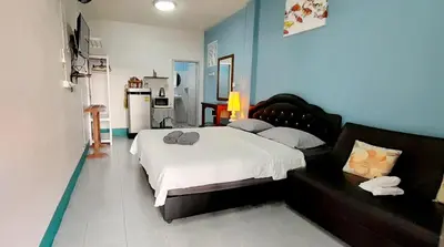 a bedroom with a large bed and a blue wall at Sala Bua Room in Karon Beach