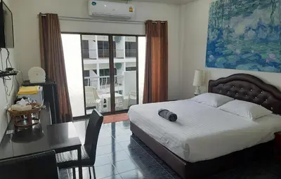 a bedroom with a bed and a desk with a table and a desk at Sala Bua Room in Karon Beach