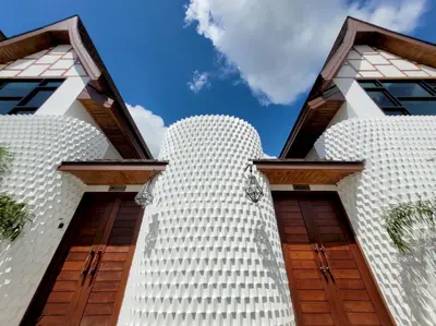 a tall white building with wooden doors at Poonsiri Varich Pool Villa Aonang in Ao Nang Beach