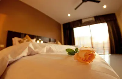 a rose on a white bed with a window at Mellow Space Boutique Rooms in Karon Beach