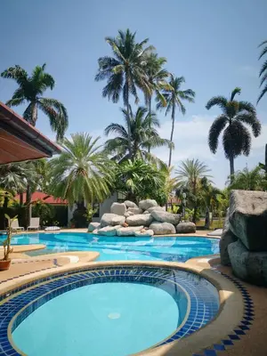 a swimming pool with palm trees in the background at Coconut Wells Phuket in Chalong