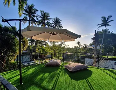 a patio with an umbrella and some green grass at Coconut Wells Phuket in Chalong