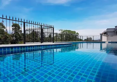 a swimming pool with a fence and blue water at NaiYang beach Title Residencies by My Home Phuket in Nai Yang Beach