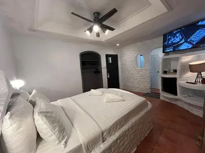 a bedroom with a white bed with a ceiling fan at Big Boys' Bed & Burger - Patong Beach in Patong Beach