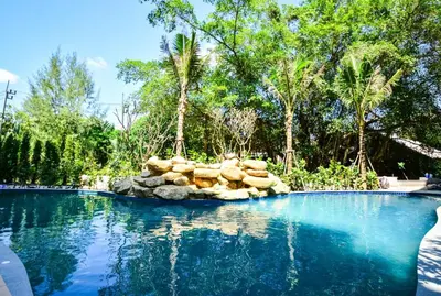 a swimming pool with a rock island in the middle at The Title Residence NaiYang in Nai Yang Beach