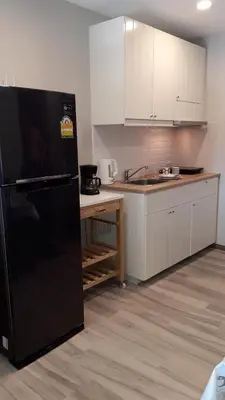 a kitchen with a black refrigerator and white cabinets at The Title Residence NaiYang in Nai Yang Beach