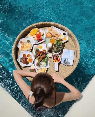 a woman laying on a table with food next to a pool at Phi Phi Maiyada Resort in Phi Phi Don
