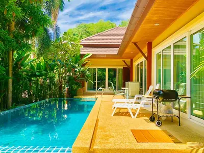 a swimming pool with chairs and a house at Thai Family karon Pool Villa \u6cf0\u5982\u5bb6\u5361\u4f263\u5367\u6cf3\u6c60\u522b\u5885 in Karon Beach