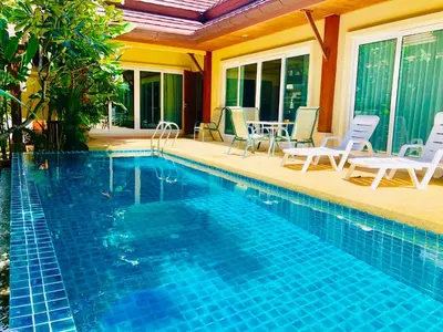 a swimming pool with chairs and a table at Thai Family karon Pool Villa \u6cf0\u5982\u5bb6\u5361\u4f263\u5367\u6cf3\u6c60\u522b\u5885 in Karon Beach