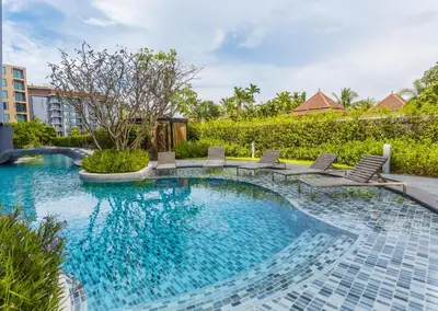 a swimming pool with chairs in a resort at The Aristo by Holy Cow, studio, mountain view in Surin Beach