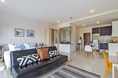 a living room with a couch and a kitchen at Chic Condo by RESAVA in Karon Beach
