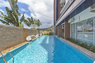a swimming pool in the side of a building at Chic Condo by RESAVA in Karon Beach