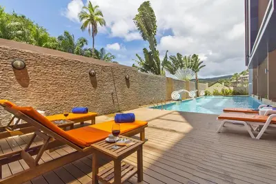 a patio with two chairs and a swimming pool at Chic Condo by RESAVA in Karon Beach