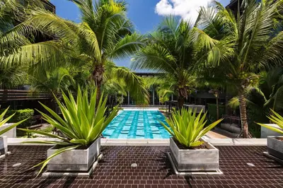 a swimming pool with palm trees in front of a building at Lucky Holidays in Saturdays Residence in Rawai Beach