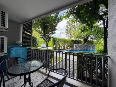a balcony with a table and chairs and a swimming pool at The Title Residencies Naiyang by Beringela in Nai Yang Beach
