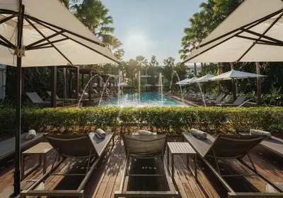 a pool with chairs and umbrellas in front of a pool at Stay Wellbeing & Lifestyle Resort in Rawai Beach