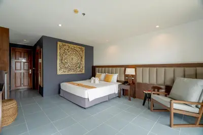 a bedroom with a bed and a couch and a chair at Blue Beach Grand Resort And Spa in Rawai Beach
