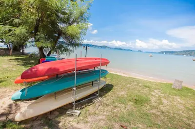 a row of boats sitting on the shore of a beach at Blue Beach Grand Resort And Spa in Rawai Beach