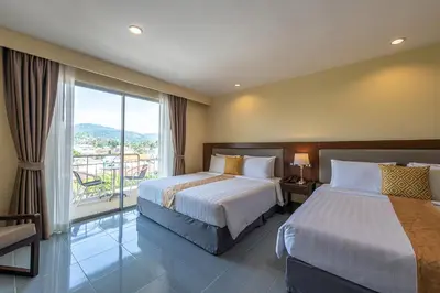 a hotel room with two beds and a large window at Blue Beach Grand Resort And Spa in Rawai Beach