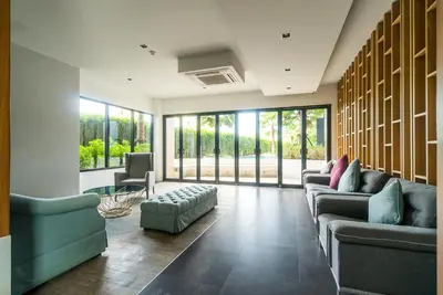 a living room with couches and chairs and windows at Apartment at Aristo Surin by Lofty in Surin Beach