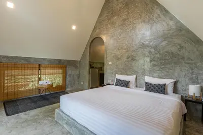 a bedroom with a large bed in a stone wall at Baan Rai Me Rak Organic Farmstay in Ban Pa Khlok