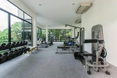 a gym with treadmills and machines in a room with windows at Karon Panorama Seaview 2 Bedroom Amazing Condo in Karon Beach