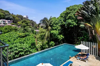 a swimming pool with a person in a chair and an umbrella at Karon Panorama Seaview 2 Bedroom Amazing Condo in Karon Beach