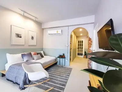 a bedroom with a bed and a white chair at Snoozy Guesthouse in Phuket Town