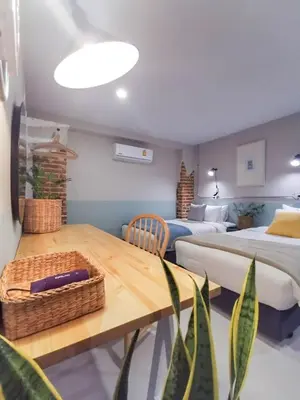 a bedroom with two beds and a table with a basket at Snoozy Guesthouse in Phuket Town