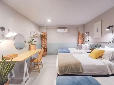 a bedroom with two beds and a desk in it at Snoozy Guesthouse in Phuket Town