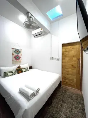 a bedroom with a white bed and a wooden door at Hanuman VIP Hostel in Bang Tao Beach