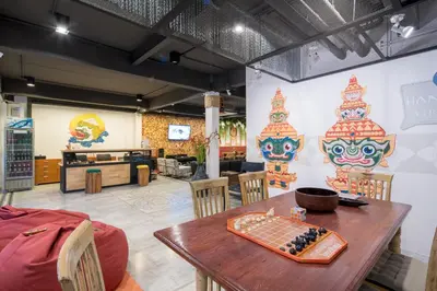 a restaurant with a table and chairs and a wall with masks at Hanuman VIP Hostel in Bang Tao Beach