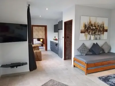 a living room with a couch and a flat screen tv at Infinity Pool Apartment at Viewpoint Villas in Nai Harn Beach