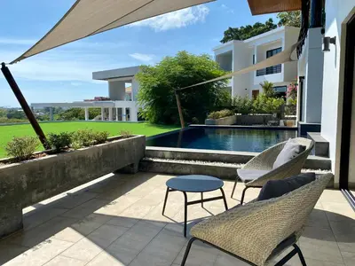 a patio with two chairs and a table and a swimming pool at Infinity Pool Apartment at Viewpoint Villas in Nai Harn Beach