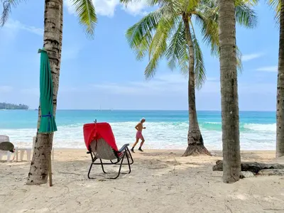 a man walking on a beach with palm trees at 360 Degree Kamala Seaview Villa in Kamala Beach