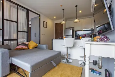 a living room with a couch and a kitchen at Palmyrah Surin Apartments by Beringela in Surin Beach