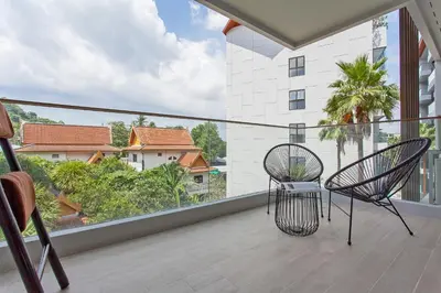 a balcony with two chairs and a large window at Palmyrah Surin Apartments by Beringela in Surin Beach