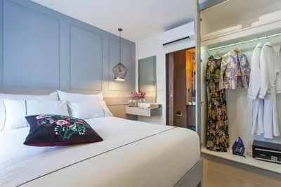 a bedroom with a white bed and some clothes at Palmyrah Surin Apartments by Beringela in Surin Beach