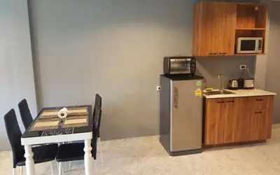 a small kitchen with a table and a refrigerator at Oasis Apartments & Bar in Karon Beach