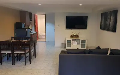a living room with a couch and a table and a television at Oasis Apartments & Bar in Karon Beach