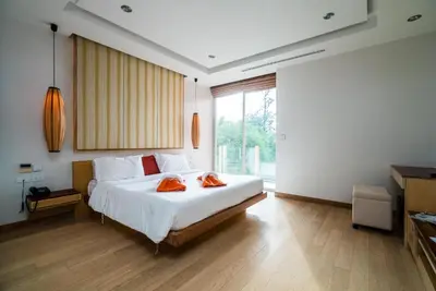a bedroom with a large bed with two orange towels on it at Bright beachfront retreat in Bang Tao in Bang Tao Beach